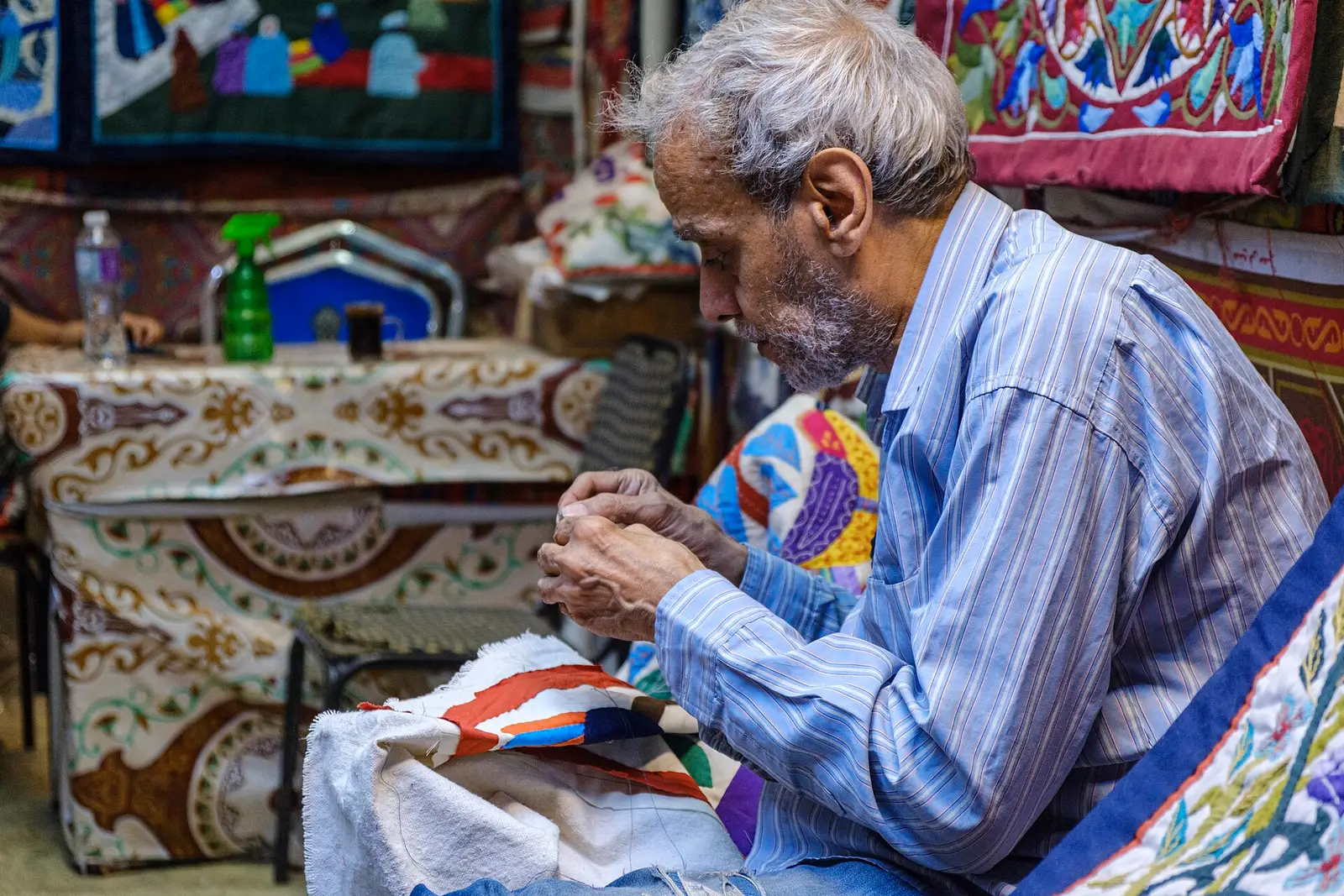 A tentmaker stitching a panel by hand